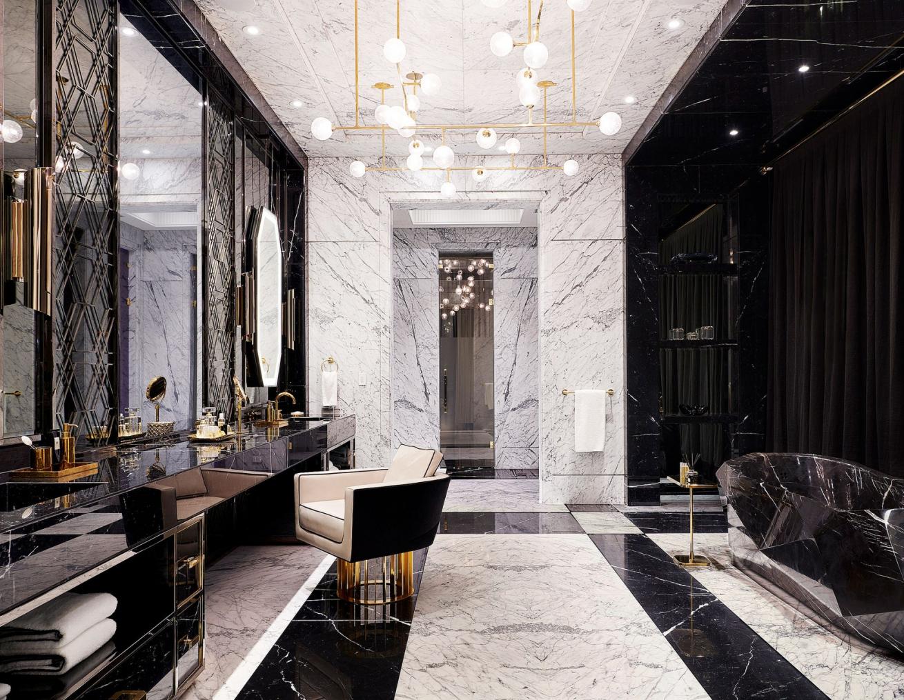 The master bath features a Nero Marquina marble vanity and tub. Custom chandelier by Lumifer; Brabbu sconces; chair by Rafauli