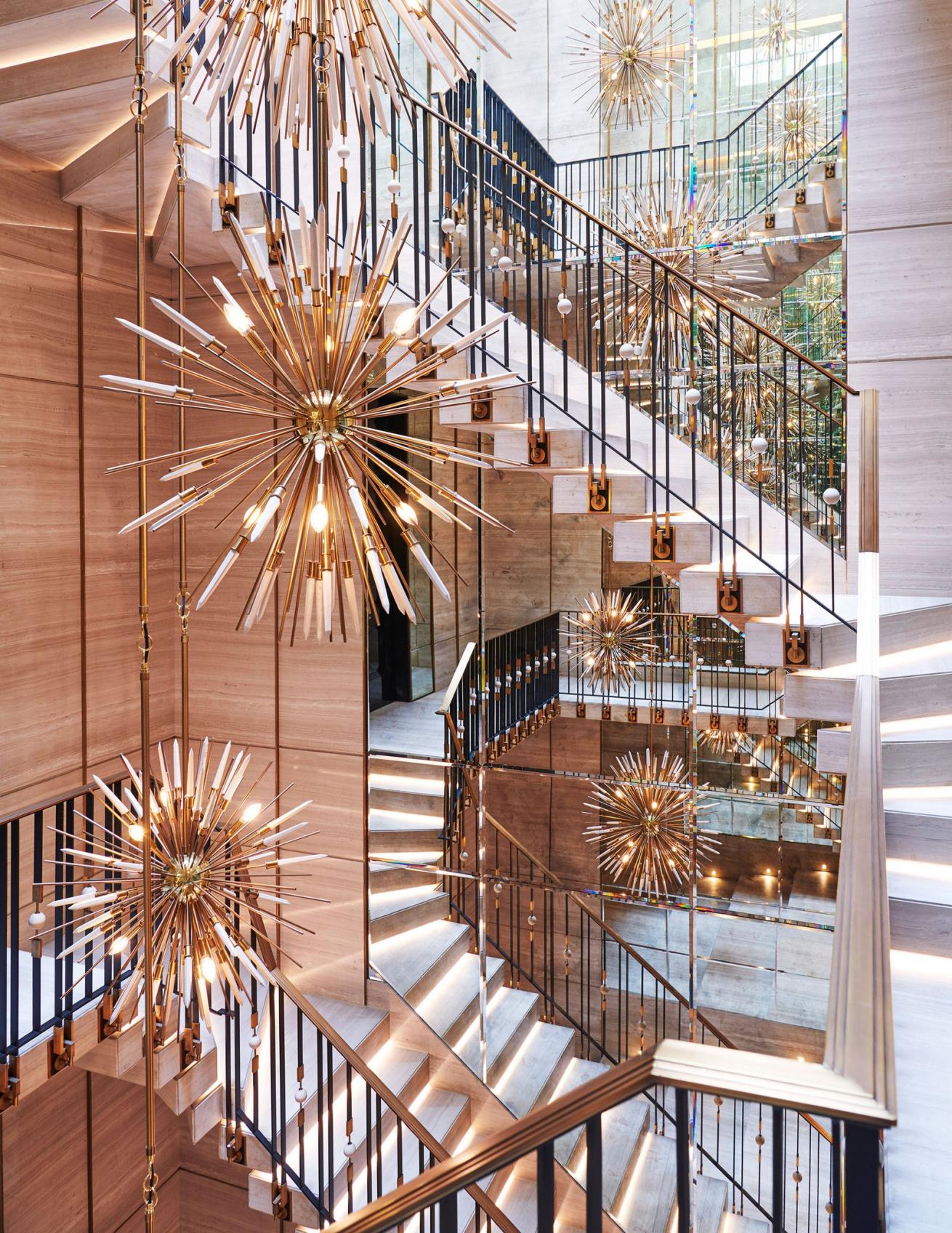 A suspended cantilevered block marble stair is adorned with chandeliers by Rafauli.